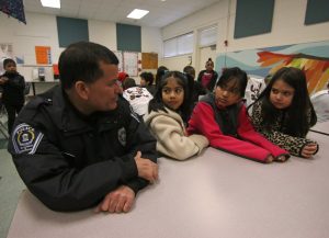 UNC Police Officer Ray Rodriguez sitting with two children during the annual Shop with a Cop event
