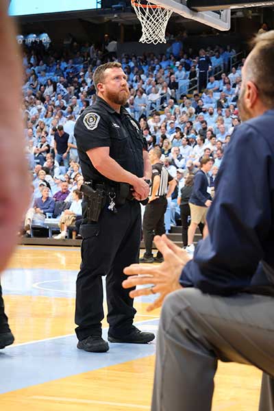 An officer is on the court to prevent unauthorized access during the game and intermission activities.